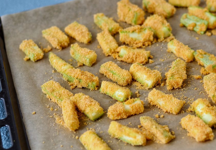 1. Этап. Кабачки в духовке без масла: Обваляйте каждый кусочек кабачка в панировочных сухарях. Выложите кабачок на бумагу для запекания. Отправьте их в духовку на 30 минут при температуре 200 градусов.