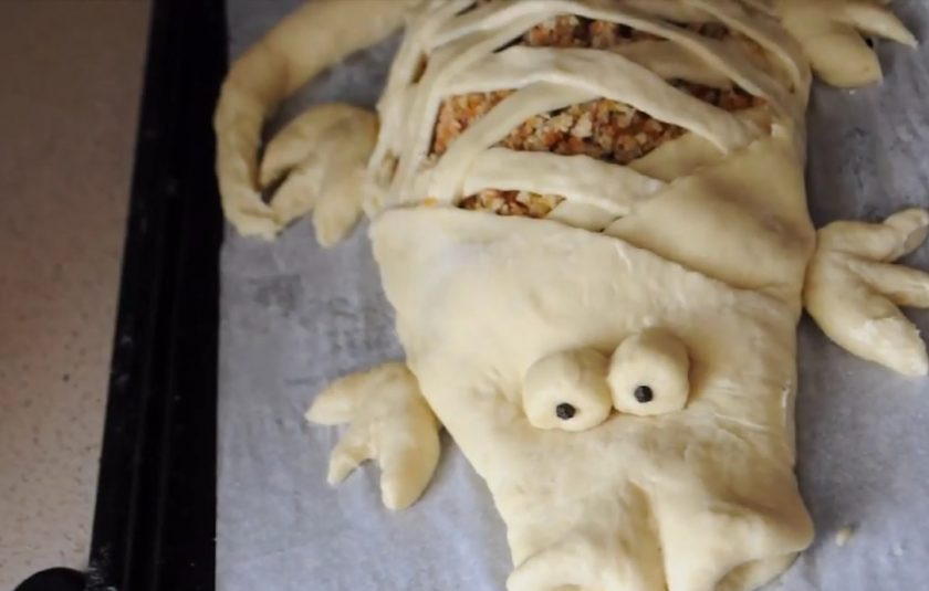 1. Этап. Пирог Крокодил: 5. Сформируйте хвост и морду крокодила. Вылепите из теста и перца горошком глаза крокодилу. Скатайте два больших и два маленьких шарика, вылепите из них лапки (можно сделать надрезы ножом в виде пальчиков).