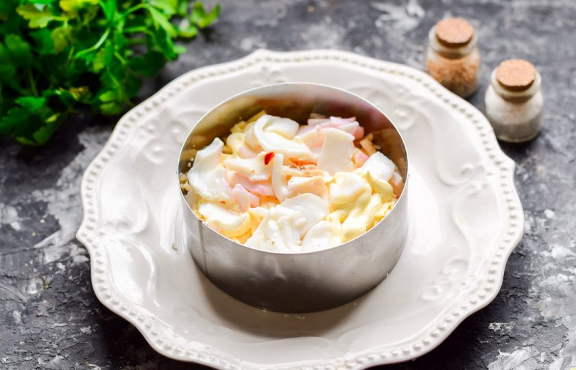 1. Этап. Салат Мимоза с кальмарами: Следующим слоем выложите нарезанные маринованные кальмары.