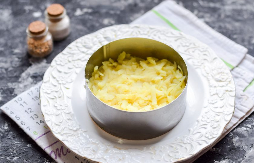 1. Этап. Салат Мимоза с красной рыбой: Отварите картофель и морковь до готовности, также сварите яйцо. Картофель очистите и натрите на средней терке, выложите первым слоем в салат.