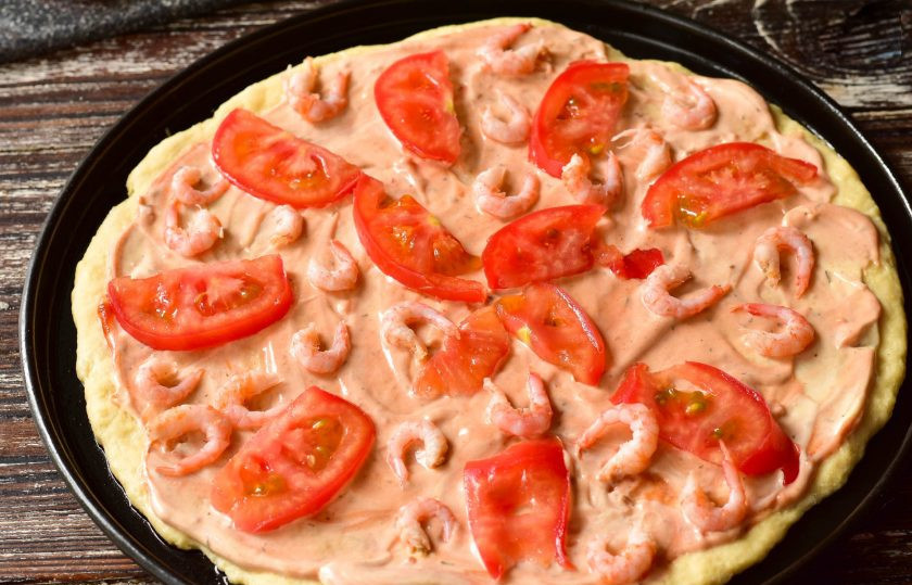 1. Этап. Пицца с креветками и рукколой: Вымойте, нарежьте и выложите помидор сверху на тесто.