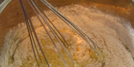 1. Этап. Пицца без дрожжей на молоке: Взбиваем яйцо с солью, добавляем молоко и соду. Взбиваем еще раз. Кладем муку и вымешиваем.