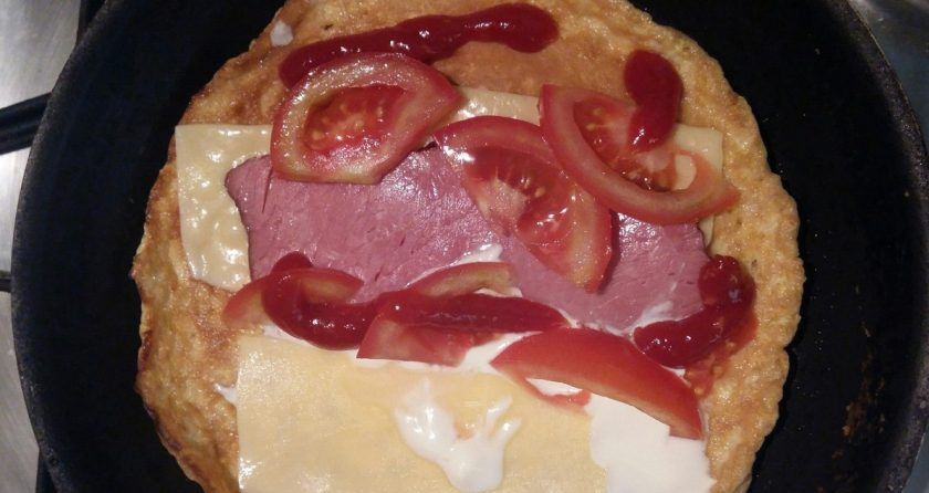 1. Этап. Омлет с овсяной кашей: Смажьте омлет майонезом и кетчупом, посолите и поперчите по вкусу, выложите кусочки сыра, ветчины и нарезанный помидор.