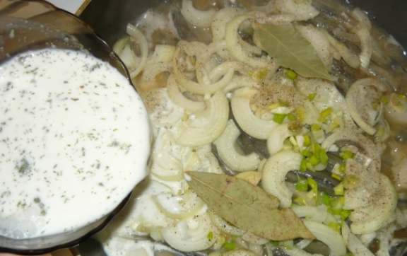 1. Этап. Мойва, тушеная с луком на сковороде: Кладем порезанный лук на рыбу, сверху вливаем сметанную смесь. Покрутите сковороду в разные стороны, чтобы мойва не прилипала ко дну. При этом переворачивать рыбу лопаткой не стоит, иначе развалится. Доводим блюдо до кипения, накрываем крышкой и готовим еще 5 минут.