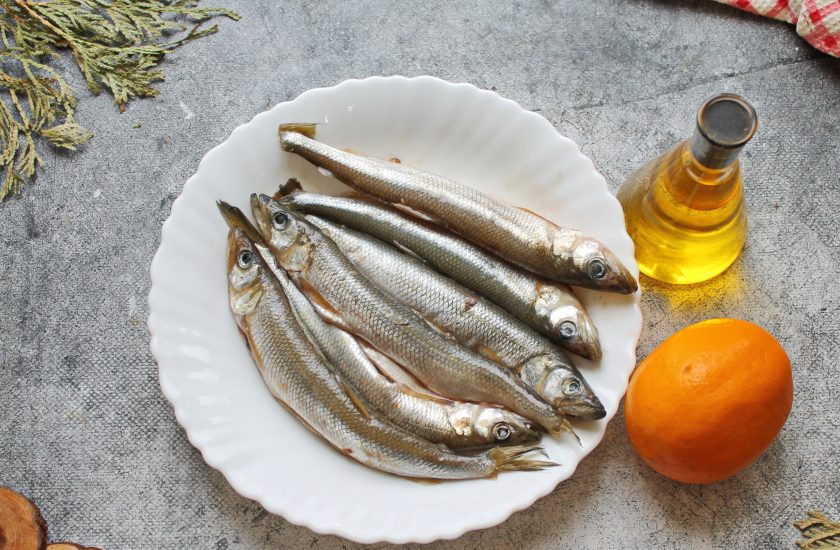 1. Этап. Корюшка на мангале: Влейте лимонный сок и растительное масло. Все перемешайте и оставьте на кухонном столе на 10-15 минут. Пока корюшка маринуется, подготовьте для приготовления в мангале угли.