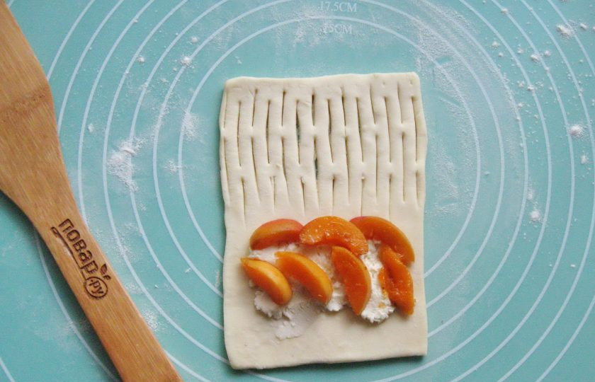 1. Этап. Слойки с творогом и абрикосами: Из вымытых абрикосов удалите косточки и мелко нарежьте. Выложите поверх творога.