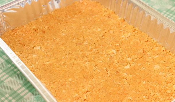 1. Этап. Торт из творога без выпечки: 2. Тщательно перемешать масло с крошкой печенья и разложить ровным слоем на дно формы. С применением силы утрамбовать корж и отправить форму в холодильник.