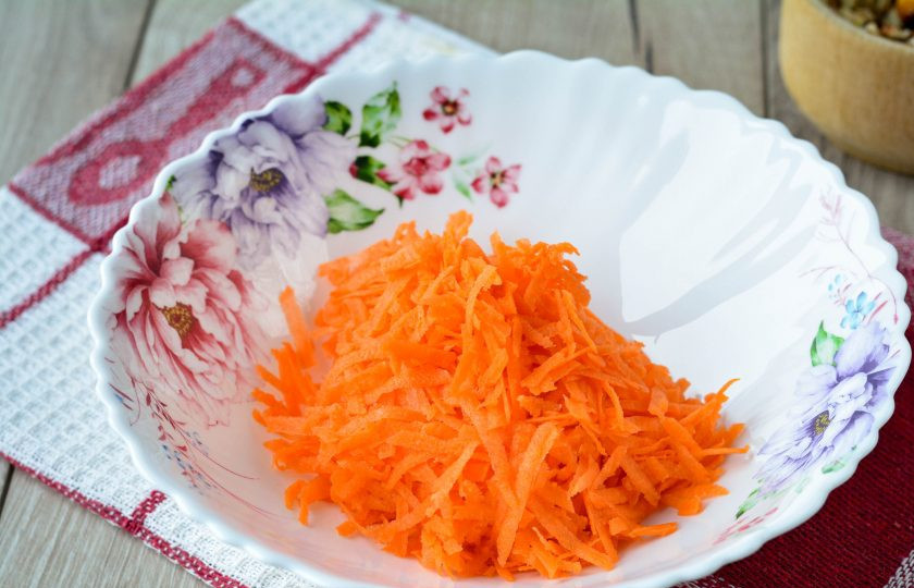 1. Этап. Салат с орешками: Натрите почищенную морковь на крупной терке и сложите в миску.