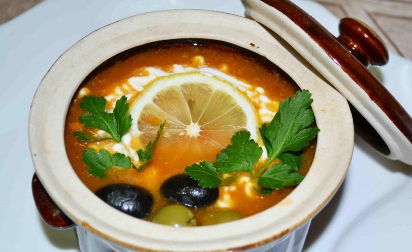 1. Этап. Солянка из рыбы: 11. Сразу после закипания достаю солянку и опускаю в нее дольку лимона, украшаю сметаной, оливками и свежей зеленью, блюдо подаю сразу.