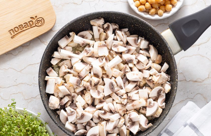 1. Этап. Нут с грибами в сливочном соусе: Шампиньоны помойте и нарежьте на кубики. Переложите в сковороду и начните обжаривать.