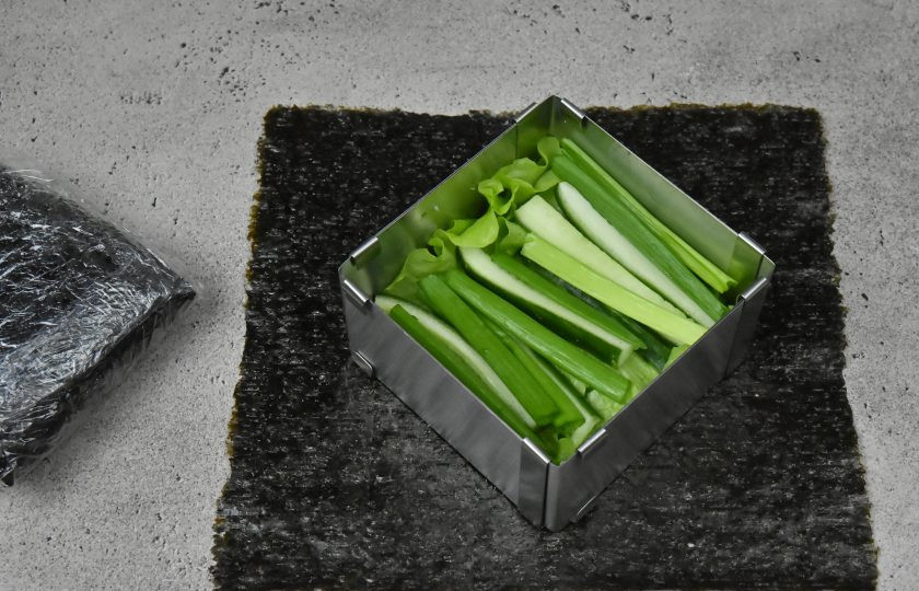 1. Этап. Суши сэндвич с креветкой: На слой сливочного сыра выложите по 2 листа салата, огуречную соломку и перья зеленого лука.