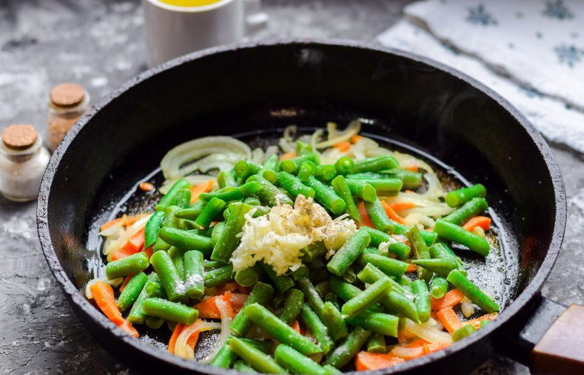 1. Этап. Стручковая фасоль с луком: Добавьте чеснок пропущенный через пресс, соль, перец. Перемешайте все и готовьте под крышкой 10-15 минут.