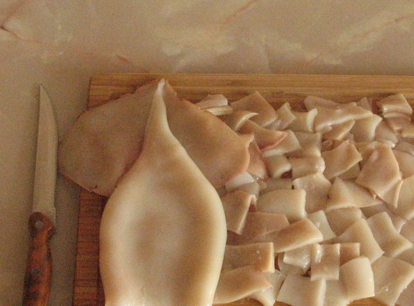 1. Этап. Кальмар в собственном соку: Кальмара обдайте кипятком, очистите и выпотрошите, а также удалите хитиновую пластинку. В конце нарежьте кусочками.