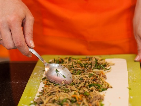 1. Этап. Слоеное тесто с фаршем: 2. Теперь раскатываем тесто в тонкий пласт. Выкладываем начинку, по желанию добавим также зелень. Сворачиваем тесто в тугой рулет. Нарезаем затем, как колбаску.