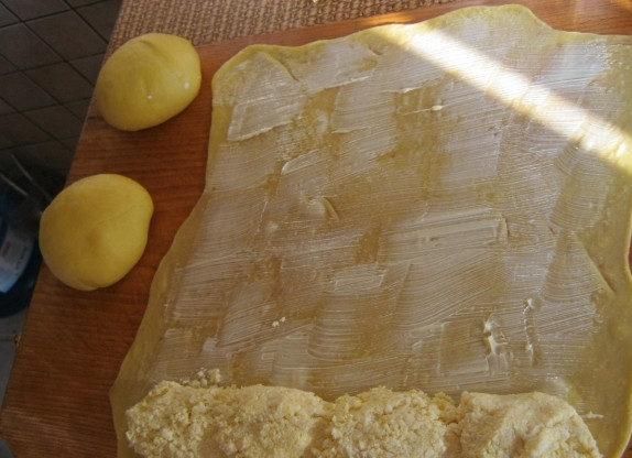 1. Этап. Испанские булочки Улитки: Смажьте тесто подсолнечным маслом, уложите на одной стороне творог — и скрутите тесто с начинкой рулетом. Потом заверните рулет в виде 