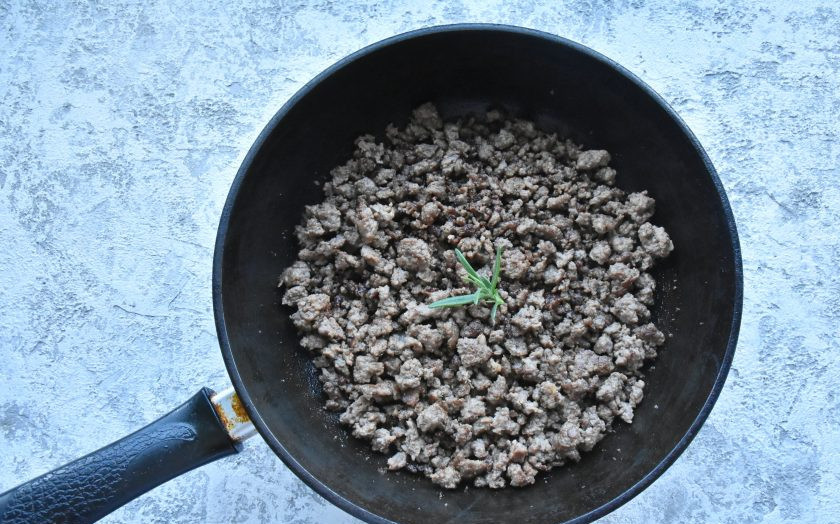 1. Этап. Лазанья с фаршем от Джейми Оливера: В сковороду влейте растительное масло, добавьте веточку розмарина, чтобы он ароматизировал масло. Добавьте в сковороду фарш и хорошо его обжарьте, помешивая и разбивая мясные кусочки деревянной лопаткой.