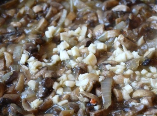 1. Этап. Паштет из шампиньонов: Когда лук станет мягким, добавьте мелко нарезанный чеснок и грибы.