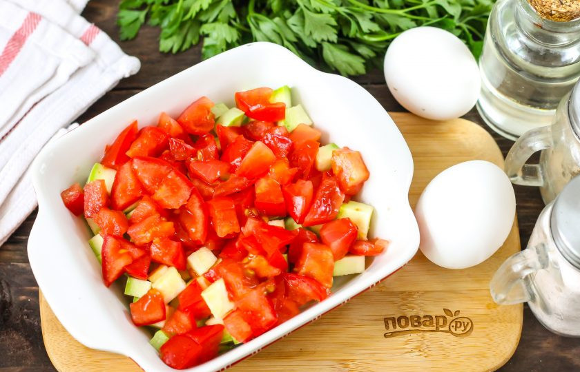 1. Этап. Овощная запеканка в микроволновке: Помидоры промойте в воде, вырежьте зеленые сердцевинки и нарежьте кубиками, добавьте в емкость.