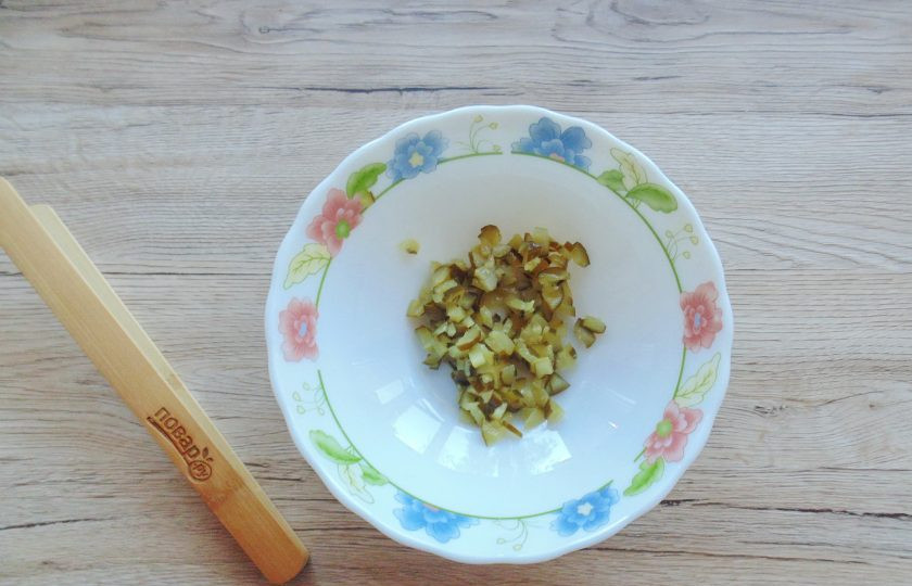 1. Этап. Салат из шпрот и кукурузы: Маринованный огурец нарежьте мелко. Переложите в салатник.