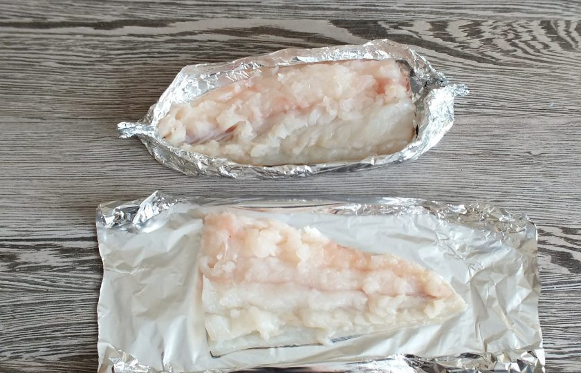 1. Этап. Пикша в духовке под сыром: У слегка подмороженной рыбы удалите хребтовую кость. Удалите все возможные косточки. Филе разрежьте на части. На небольшой лист фольги выложите один кусочек филе и сформуйте лодочку.