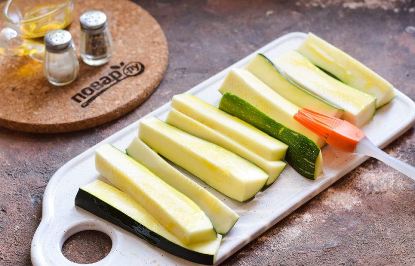 1. Этап. Цукини с сыром в духовке: Цукини нарежьте дольками, смажьте каждую дольку растительным маслом.