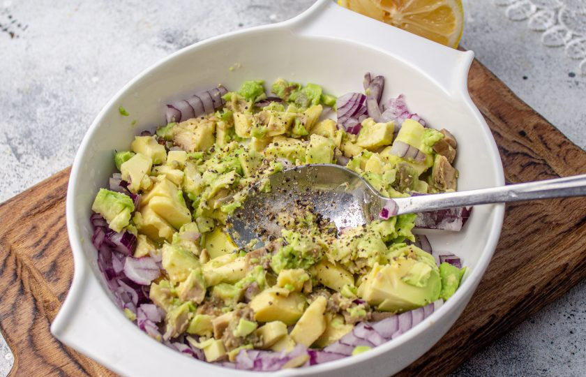 1. Этап. Праздничный легкий салат с семгой и авокадо: Авокадо выберите спелый. Разрежьте его пополам, удалите косточку и извлеките из кожуры. Мякоть нарежьте небольшим кубиком, добавьте к луку, влейте сок лимона, поперчите и добавьте оливковое масло, перемешайте.