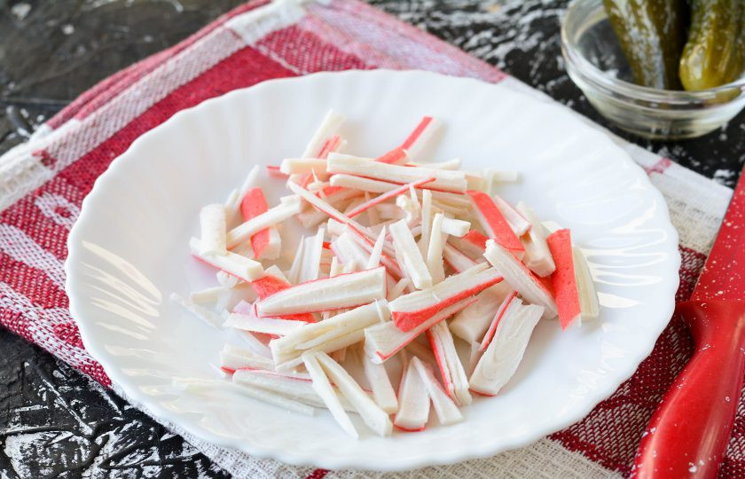 1. Этап. Крабовый салат с соленым огурцом: Нарежьте крабовые палочки удлиненными полосками.