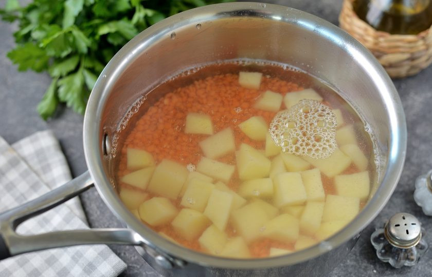 1. Этап. Суп с чечевицей и баклажанами: Промойте чечевицу до чистой воды, нарежьте картофель кубиком, переложите все это в сотейник, залейте водой. После закипания варите минут 10.