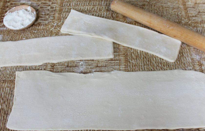 1. Этап. Греческая улитка: Слоеное тесто разделяем на 3 части. Посыпаем мукой. Каждый кусок теста раскатываем продолговатой полоской. Как на фото.