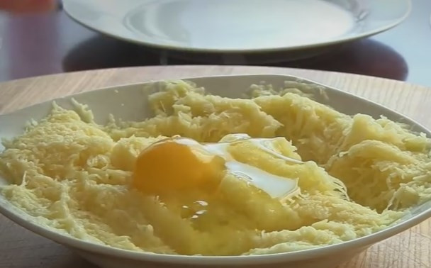 1. Этап. Отбивная Медвежья лапа: 4. Картофель нужно очистить и натереть на мелкой терке. Посолите и слейте лишнюю жидкость. Добавьте яйцо, перемешайте.