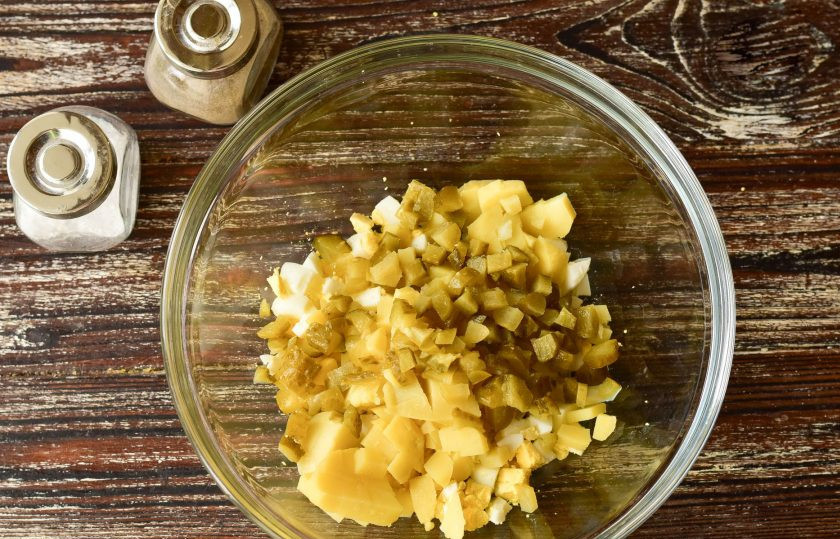 1. Этап. Оливье с печенью трески: Соленые огурцы выложите на разделочную досочку, срежьте с двух сторон края, остальную часть нарежьте и отправьте в миску.