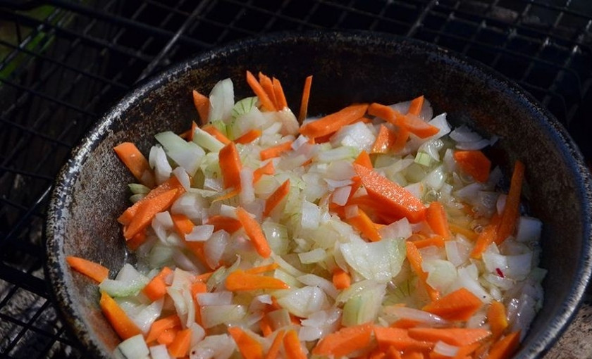 1. Этап. Борщ в казане на костре: Морковь и лук помойте, почистите и измельчите ножом. Обжарьте их в масле до полуготовности.