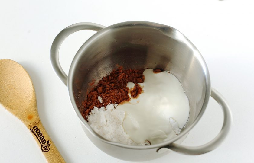 1. Этап. Глазурь из сметаны: В небольшую кастрюльку или сотейник насыпьте какао и сахарную пудру. Добавьте сметану и поставьте на небольшой огонь.