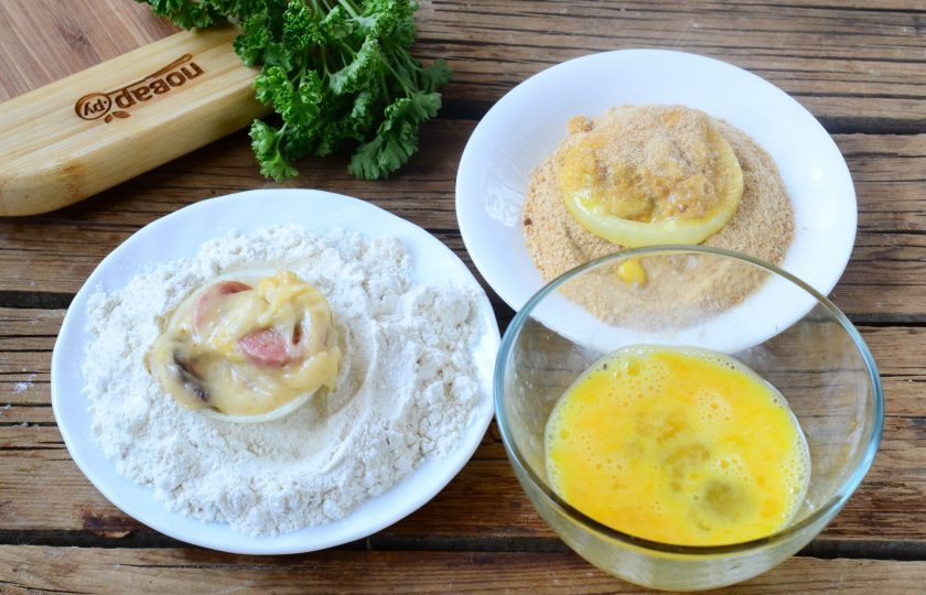 1. Этап. Хот-дог в луковых колечках: Поставьте разогреваться растительное масло в небольшой сковороде или кастрюльке. Подготовьте все для панировки – взбейте яйцо с небольшим количеством перца и соли, в небольшие тарелочки насыпьте немного муки и панировочных сухарей. Каждое луковое колечко с начинкой обмакните сначала в муку, затем в яйцо, а затем в панировочные сухари.