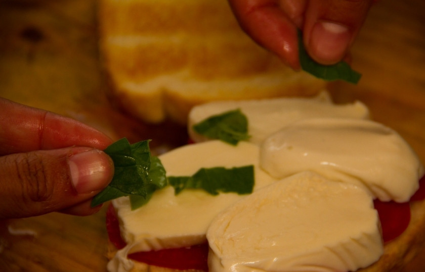 1. Этап. Бутерброды с моцареллой: Сверху чеснока положите кружочки помидора и ломтики моцареллы. Нарвите листья базилика и посыпьте моцареллу ими.