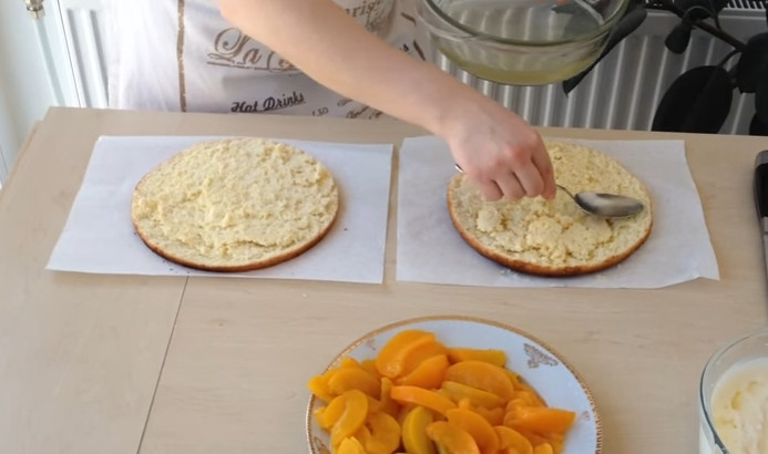 1. Этап. Фруктовый торт: 9. Достаете бисквит и остужаете его, затем разрезаете на 2 коржа, каждый пропитываете соком из консервированных персиков. Один бисквит смазываете кремом, выкладываете консервированные персики, накрываете вторым коржом.