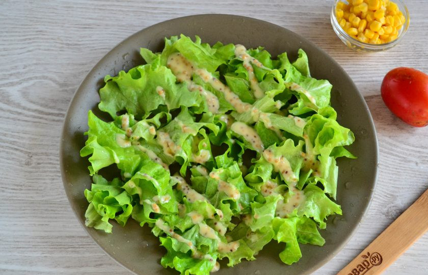 1. Этап. Салат с гренками: Теперь начинаем собирать салат. Листья салат промойте, порвите на небольшие куски и выложите на большую плоскую тарелку. Сверху слегка полейте подготовленным соусом.