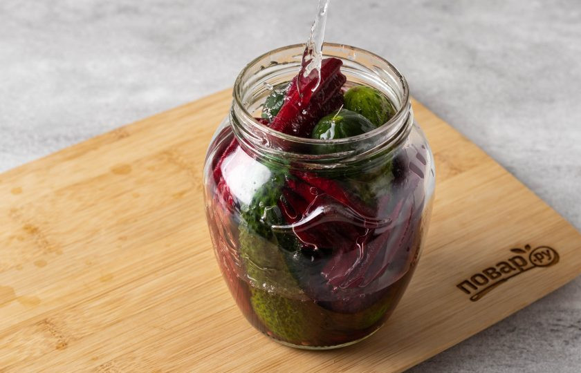 1. Этап. Огурцы маринованные со свеклой на зиму: Влейте горячую воду в банку. Прикройте крышкой, оставьте на 10 минут.