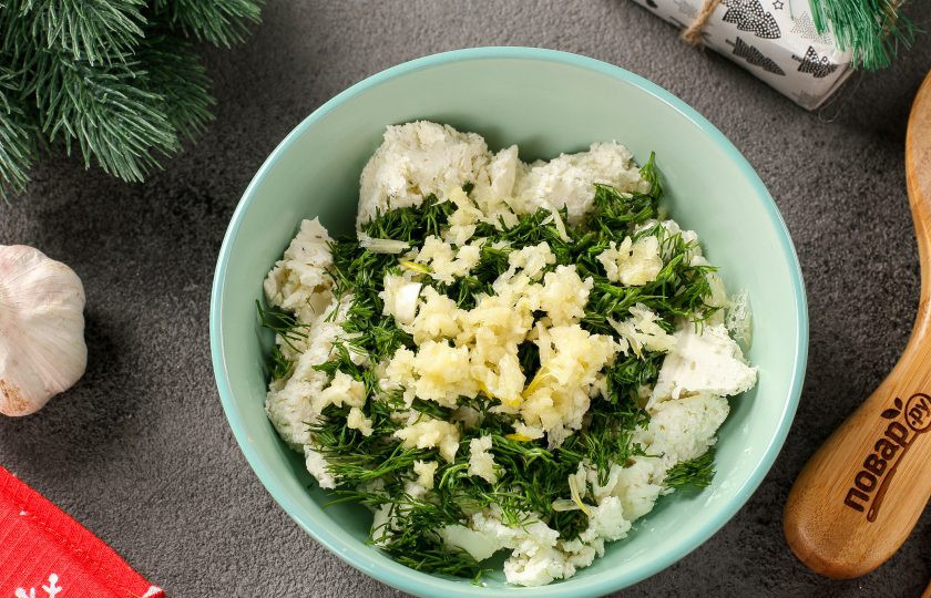 1. Этап. Новогодняя закуска Взгляд дракона: Соедините сыр, измельчённую зелень и давленные зубчики чеснока. Перемешайте. Это будет начинка для закуски.