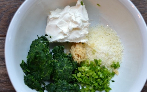 1. Этап. Куриные грудки с сыром и беконом: 2. В миску выложите сливочный сыр, тертый сыр, измельченный зеленый лук, измельченный шпинат, посолите и поперчите.