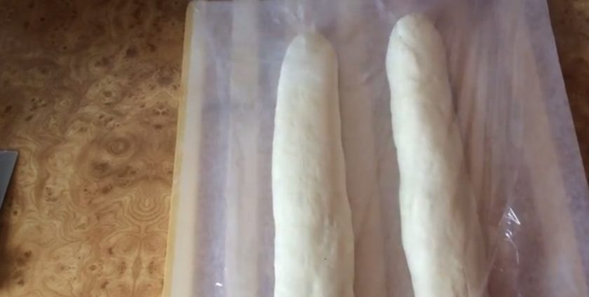 1. Этап. Французский багет на закваске: 6. Сформируйте батон, прорабатывая каждый шов. Раскатайте батон в багет и выложите на лист бумаги для выпечки. Накройте пищевой пленкой и оставьте на 2-3 часа. Сделайте надсечки на багетах и сбрызните их водой.