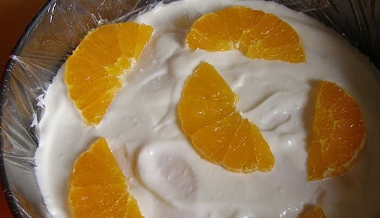 1. Этап. Творожный торт с желе и фруктами: Застилаем разъемную форму пищевой пленкой и выкладываем немного творожной смеси, а на нее - дольки апельсина. Не выкладывайте слишком много фруктов, творог может не застыть.