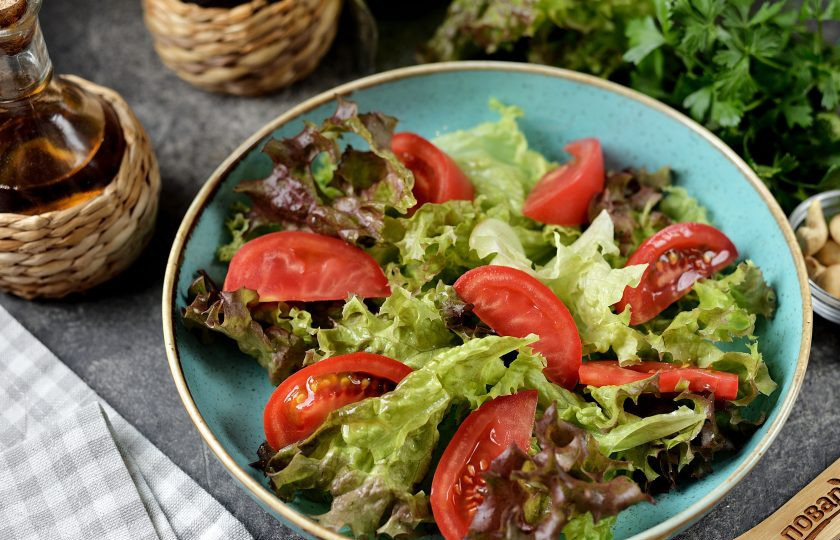 1. Этап. Салат с печенью, сладким перцем, помидорами и орехами: Удалите на помидоре место плодоножки, нарежьте его небольшими ломтиками, разложите на латук.