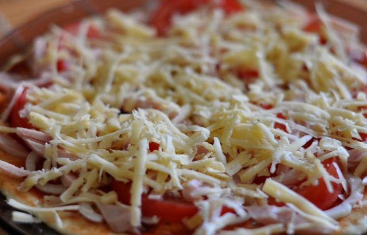 1. Этап. Пицца Минутка в микроволновой печи: Теперь посыпаем стол мукой и выкладываем на него приготовленное тесто, раскатываем его в очень тонкий круглый пласт, чем он тоньше, тем быстрее приготовится пицца. Перекладываем нашу основу для пиццы на специальную плоскую тарелку для микроволновки, смазываем тесто томатной пастой и посыпаем специями. Выбранные для начинки продукты нарезаем небольшими кусочками и выкладываем их на пласт теста, солим немного, сверху посыпаем все обильно сыром.