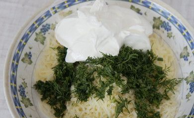 1. Этап. Бризоль с сыром: Когда готова первая мясная лепешка, можно заняться подготовкой начинки. Начинку мы будем выкладывать на горячие бризоли, поэтому лучше ее подготовить заранее. Натираем на крупной терке сыр, чистим и измельчаем чеснок. Режем зелень укропа. Добавляем сметану или майонез и все перемешиваем.