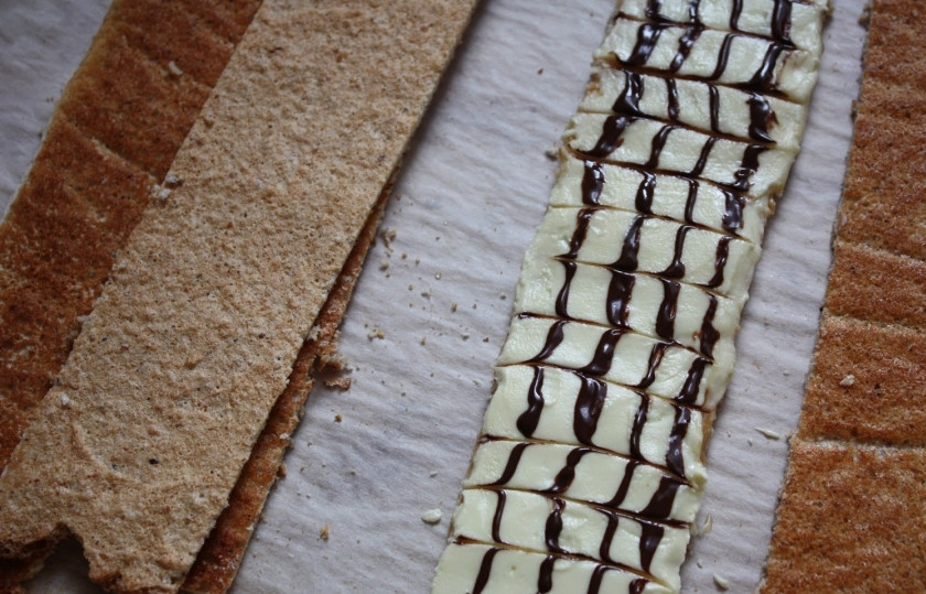 1. Этап. Пирожное Эстерхази: 3. 20 грамм масла комнатной температуры нарезаем кусочками, смешиваем с белым шоколадом и растапливаем на водяной бане, затем наносим на 1 полоску коржа. Растапливаем черный шоколад с 20 граммами масла. Зубочисткой наносим полоски на корж с белым шоколадом, делаем характерный рисунок.