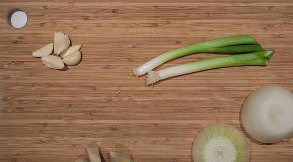 1. Этап. Буженина на сковороде: 2. Пока обжаривается мясо, можно заняться овощами. В рецепт приготовления буженины на сковороде используется луковица, которую необходимо очистить (резать не нужно), очищенный и нарезанный пополам чеснок, а также немного зеленого лука. Еще один ингредиент данного рецепта - корень имбиря. Его нужно очистить и нарезать крупными кусочками. Очищенные овощи добавить на сковороду (кроме лука) и обжарит вместе с мясом 3-4 минуты.