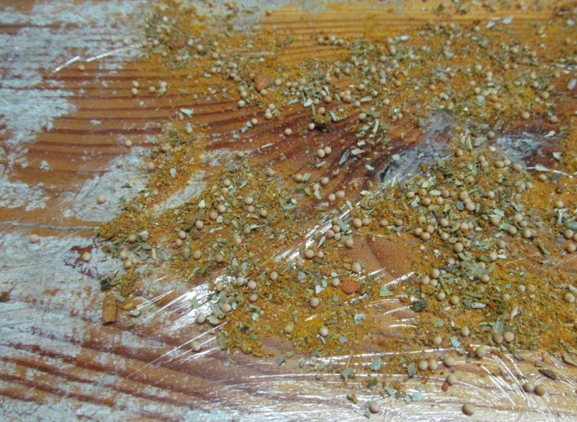 1. Этап. Праздничный мясной рулет: На дощечке расстелите пищевую пленку и равномерно посыпьте ее половиной специй.