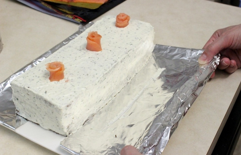 1. Этап. Торт с копченым лососем: Смажьте полученный торт тонким слоем сливочного сыра, после чего аккуратно удалите нижний слой фольги