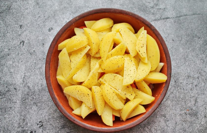 1. Этап. Оленина с картошкой в духовке: Картофель почистите, порежьте на дольки и выложите сверху. Все посолите и влейте воду.